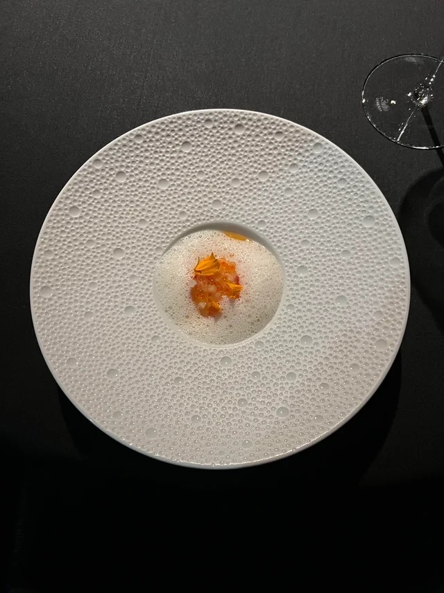Eén gedekt bord met een gerecht, op een donkere tafel